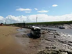 Rive boueuse avec un petit bateau. L'eau peut encore être vue dans le canal vers la droite.