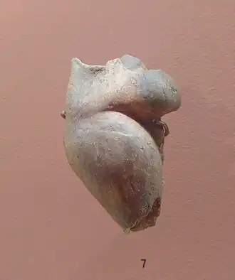 Photographie de la sculpture d'une femme corpulente et sans tête sur fond beige