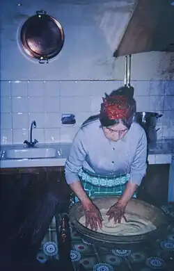 Grand-mère pied noire roulant la semoule dans une gasâa en noyer.