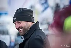 Portrait, de profil, très souriant, bonnet sur la tête.