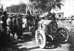 Photo d'un homme et d'un passager assis dans une voiture entourée par le public.