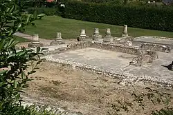 Photographie des vestiges d'un habitat antique avec des bases de colonnes entourant une cour.