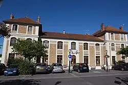 Vue d'un bâtiment en pierre de taille et meulière, pavillon central à 1 étage ; ailes à 2 étages.