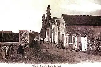 Vue d'une rue au début du XXe&nbsp;siècle ; jardin à gauche, maisons à droite.