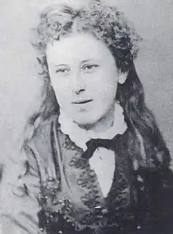 Portrait noir et blanc d'une jeune fille blanche aux cheveux longs bouclés, yeux rêveurs et léger sourire