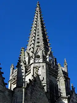 La flèche octogonale vue en contre-plongée depuis la façade méridionale. À l'angle sud-ouest, escalier d'accès à la chambre des cloches et à la balustrade flamboyante.