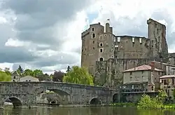 Photographie du château de Clisson prise en avril 2009 depuis la rive sud est opposée ; les hautes ruines se détachent sur fond de ciel nuageux ; au premier plan coule la Sèvre nantaise enjambée par un pont de pierre.