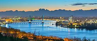 Vue large de la ville éclairée de nuit, avec le pont Jacques Chaban-Delmas en fond.
