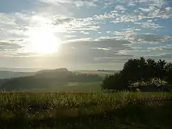 Paysage de moyennes montagnes : au premier plan des forêts et des champs, à l'arrière-plan des montagnes.