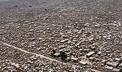 Photo prise de haut d'un vaste cimetière. Une route passe à travers l'étendue de constructions.