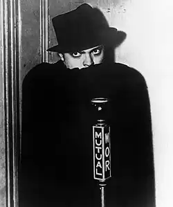 Orson Welles grimé en The Shadow. Photographie promotionnelle d'une adaptation radiophonique des aventures du justicier des pulps (vers 1937-1938).