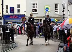 Des policiers à cheval déambulent parmi des gens.