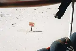 Vue depuis un autobus d'un panneau Mines, Mineen et probablement mine en arabe, planté dans le désert.