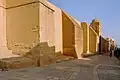Mur et contreforts de la façade occidentale de la mosquée. Des banquettes de briques se trouvent à la base du mur, notamment entre les contreforts.