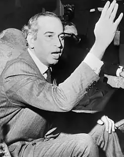 Bhutto, assis, salue en levant le bras