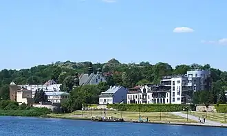 Le tumulus vu depuis la Vistule, avec au premier plan les bâtiments de Półwieś Zwierzyniecka et le complexe monastique des Norbertines.